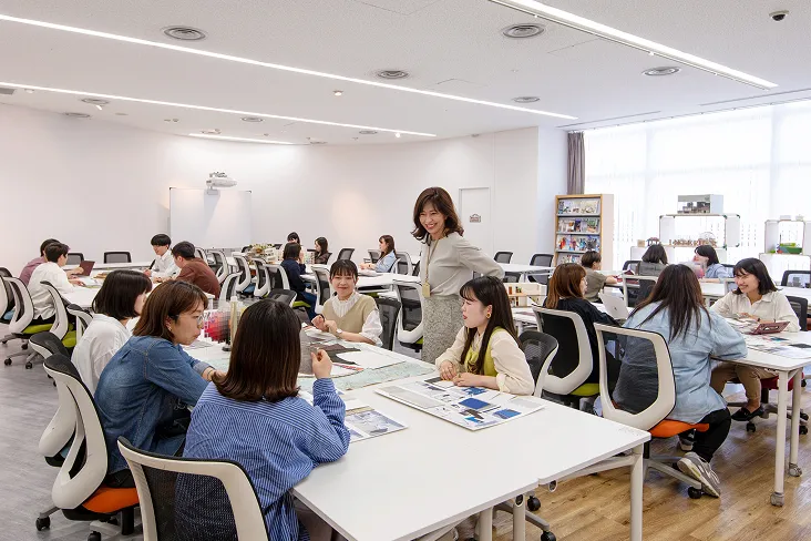 白を基調にした明るい室内に洗練されたデザインのデスクとチェアが並び、和気あいあいと授業が行われている様子