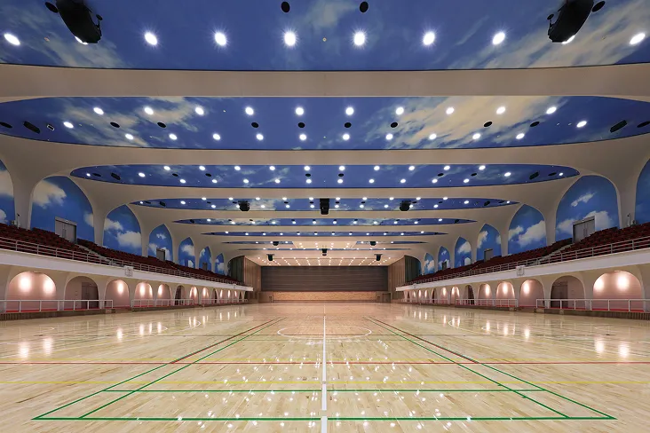 天井と二階の観客席の壁に施された青空の内装が映える、広大な室内競技施設の様子