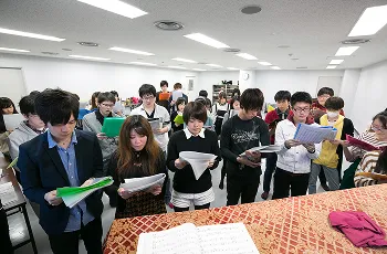 講師の周りに集まり譜面を読んでいる生徒達の風景