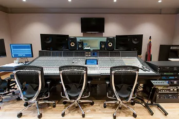 三人が並んで座れるミキサーテーブルを中心に複数のスピーカーや音響機器がコンパクトに入りされた室内