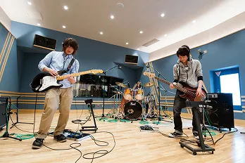 ヘッドホンを付けた生徒二人がエレキギターを弾いている様子