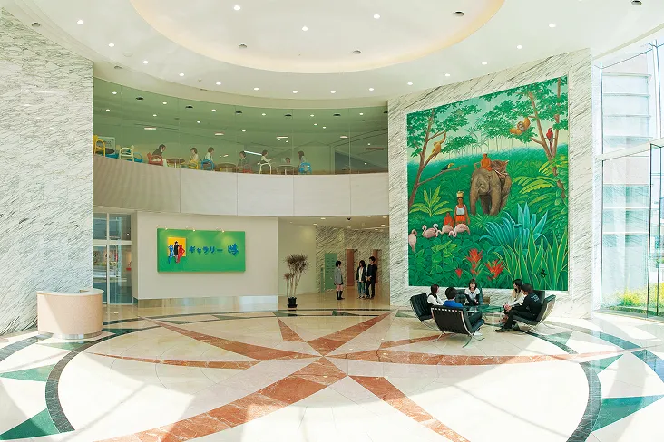 大理石調の内装に自然光が差し込む、明るく開放感のあるエントランスホール