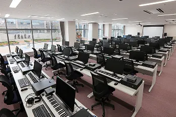 並んだPC1台ずつにキーボードと音響機器が完備され、ガラス張りの壁の向こうに庭園を眺められる広々とした空間