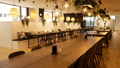 天井や目線の高さの壁の上に設置された緑が柔らかさを醸し出す、調和に満ちたカフェのような風景