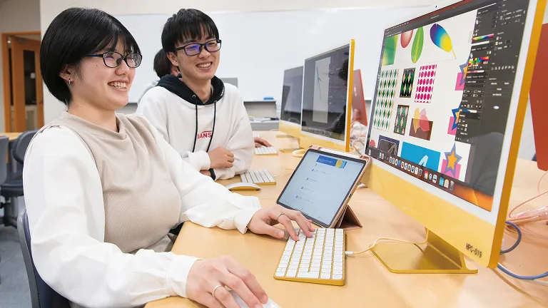 笑顔でパソコンの操作をしている学生