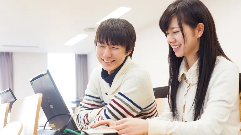 学生が笑顔でパソコン操作をしている様子
