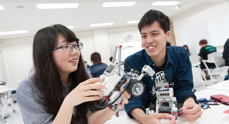 学生が組み立てたロボットを持って話す様子