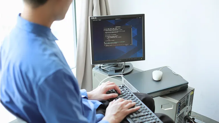 学生がパソコンモニタを見つめながらキーボード入力をしている様子