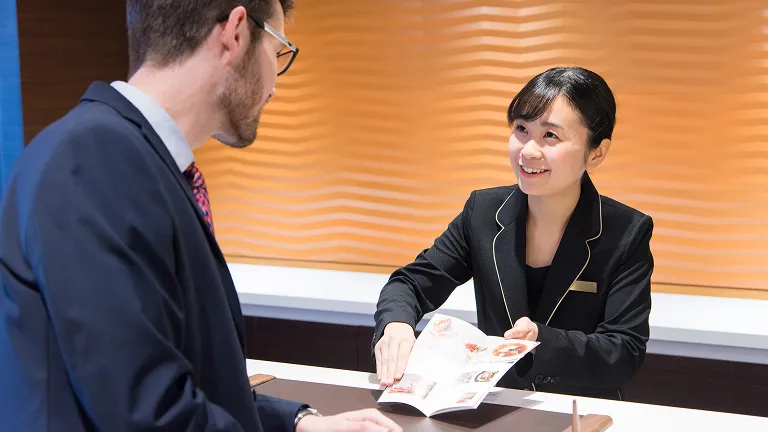 学生がホテルパンフレットを使いながら英会話学習をする様子