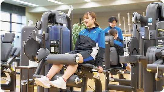 トレーニングマシンを使用している女性2人と、見守っている男性の様子