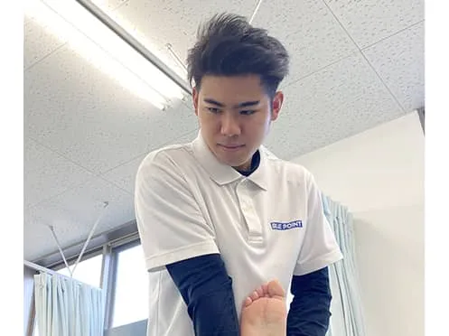 うつ伏せになっている人に施術をする学生と、指導している講師の様子