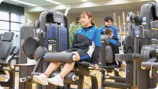 トレーニングマシンを使用している女性2人と、見守っている男性の様子