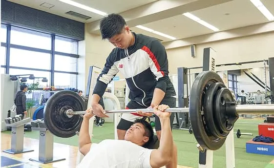 トレーニングマシンを使用している人をサポートしている様子