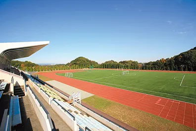 階段状の観客席を持つ総合グラウンドと8レーンあるプールの風景