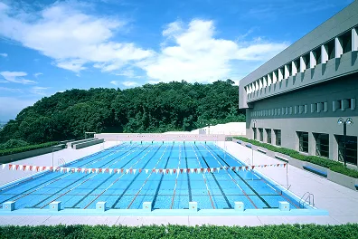 階段状の観客席を持つ総合グラウンドと8レーンあるプールの風景