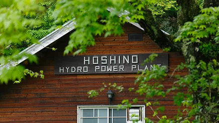 HOSHINO HYDRO POWER PLANTと表示された看板が掲げられ緑に囲まれた木造建物