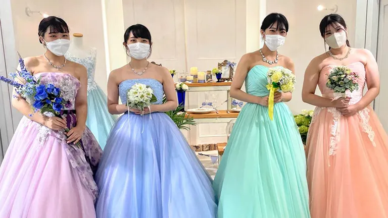 ブーケを持ってカラフルなドレス姿で並ぶ学生