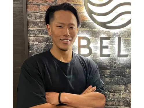 トレーニングマシンを使用している男性と、サポートをしている男性と女性の様子