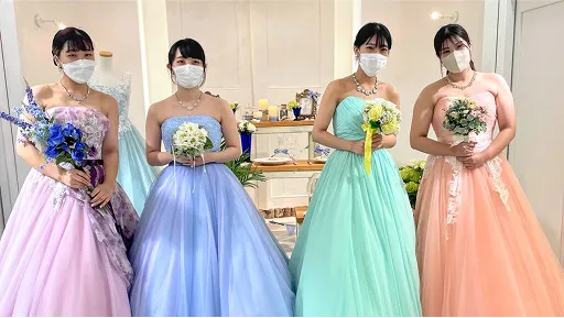 ブーケを持ってカラフルなドレス姿で並ぶ学生