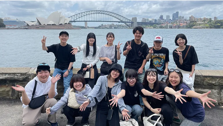 屋外で集まってポーズをとる学生たち