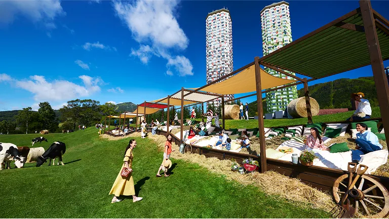 巨大牧草ベッドが並ぶ芝生広場で寛ぐ人々