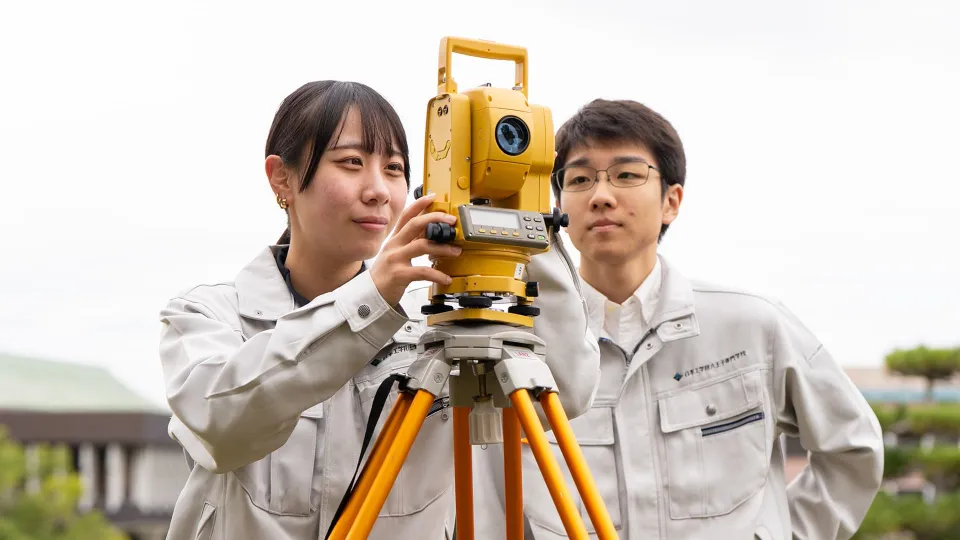 二人の学生が測量の実習をしている様子