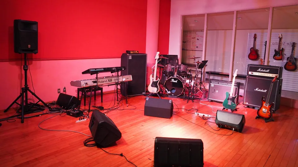 広い空間と木製の床が特徴で、複数の楽器が設置されたスタジオ