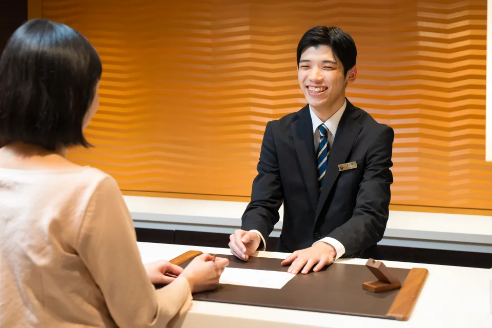 学生たちが実習で講師からフロントでの接客について学ぶ様子