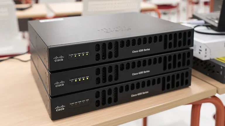 黒く四角い金属性のシスコのルーター筐体が3つ積んである様子