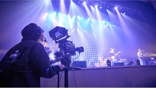 学生がステージ上で歌っている人を撮影している様子