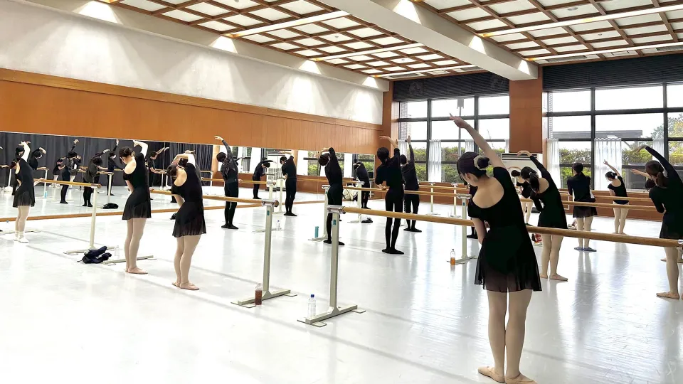 開放感がある高い天井の稽古場で、鏡の壁を背に楽しそうに稽古をする生徒達の様子
