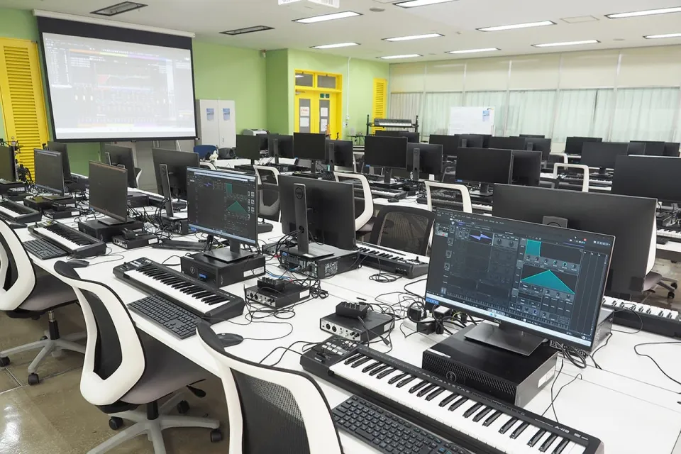 キーボードなどDTM作業に必要な機材が接続されたPCが並ぶ室内