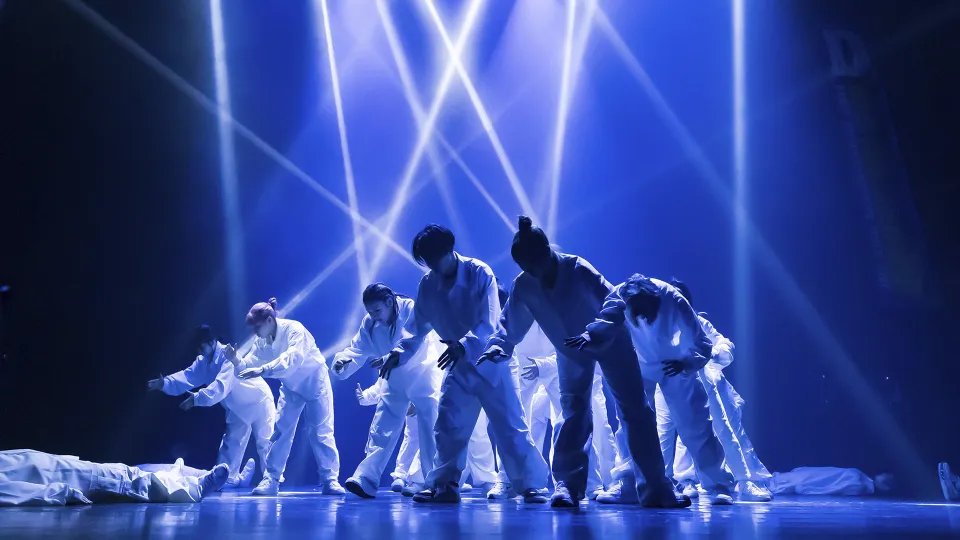 スポットライトの下で腕を広げ、ポーズを決めるオールドスクールダンスチーム