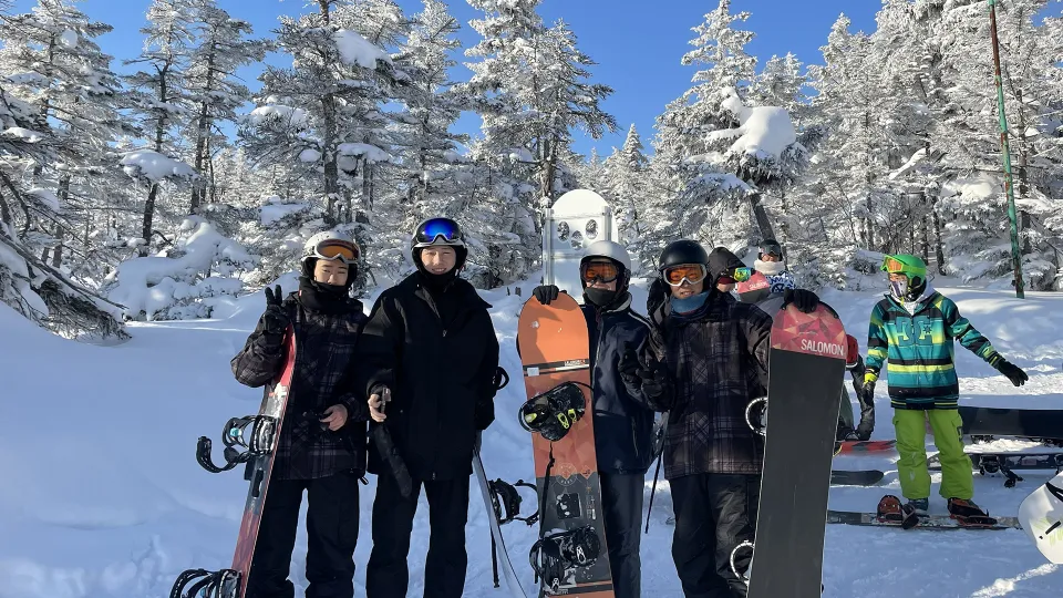 雪山のゲレンデで、スノーボードを持った学生たちの修吾写真
