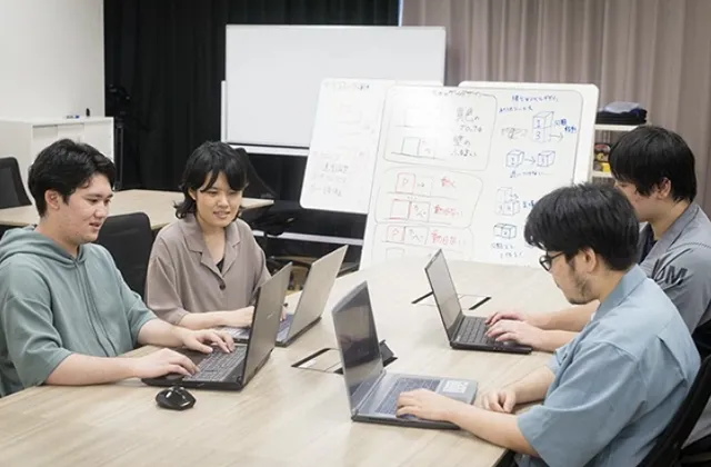 4人の学生が、ノートPCを使ってプログラミングを行なっている
