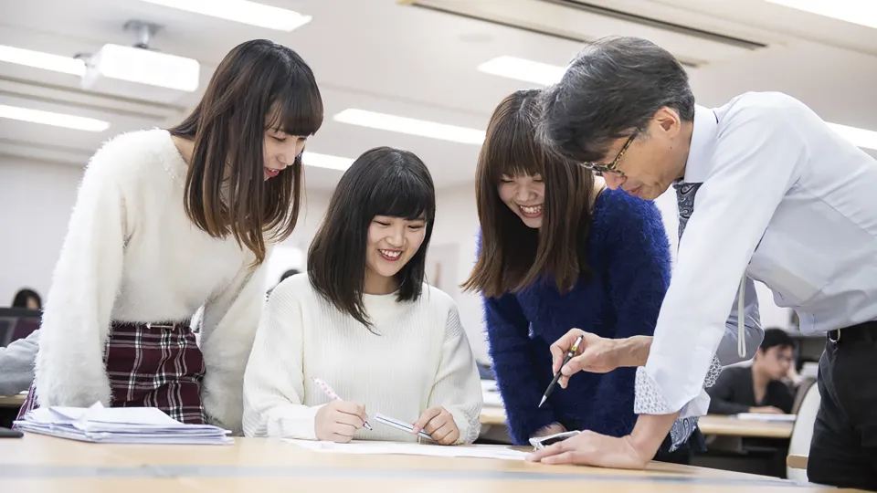 女性の学生3名に製図について教える先生
