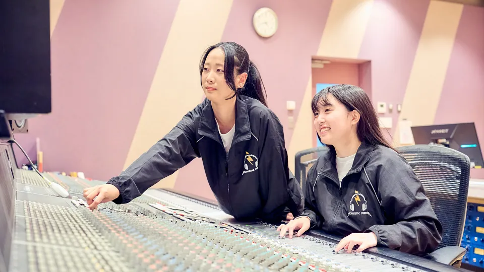 笑顔でミキシング作業をする2人の学生