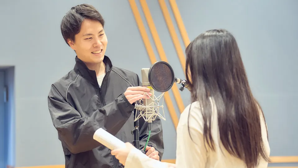 アフレコ用のマイクをセッティングする学生と台本を持った声優