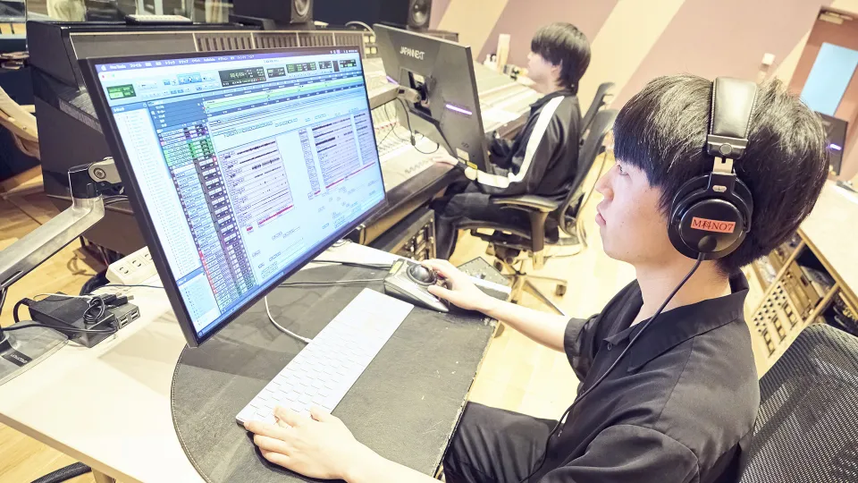 ヘッドフォンをしてPro Toolsを操作する学生