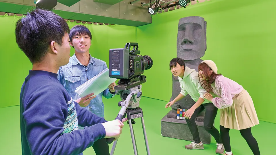 グリーンバックのセットで映像制作する学生たち