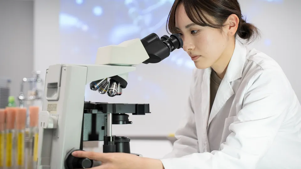 真剣な表情で顕微鏡を覗き込む学生