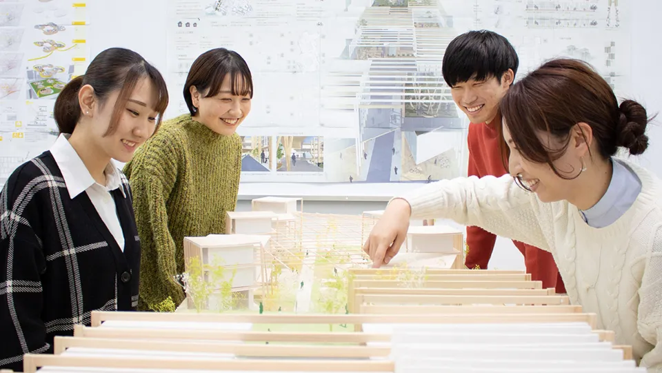 建築模型を囲み談笑する学生たち