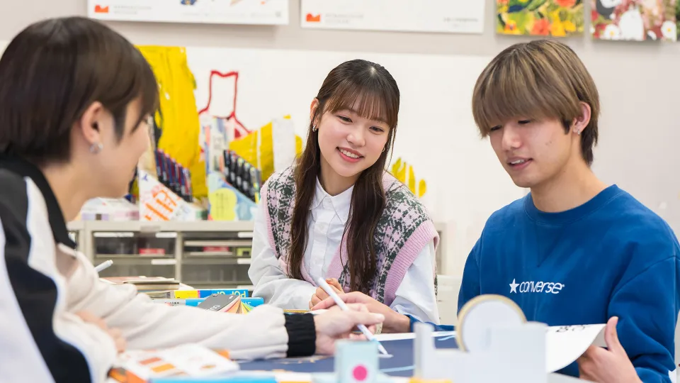 3人の学生が会話しながら作業している様子