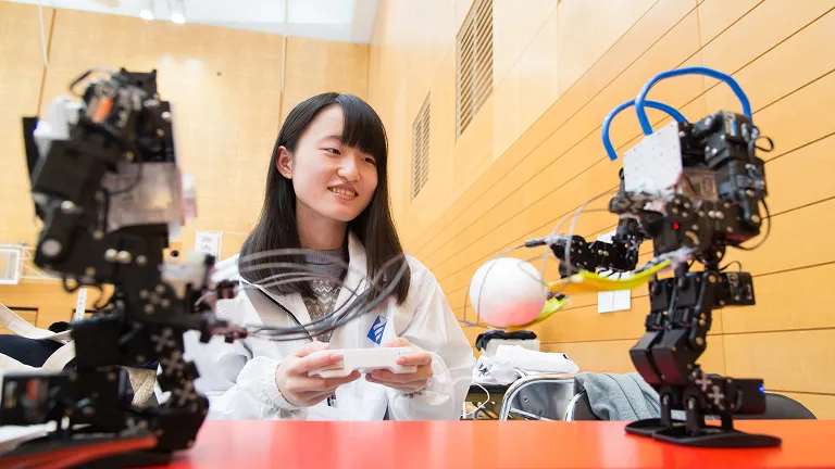 学生が二足歩行ロボットの動きを操作している様子