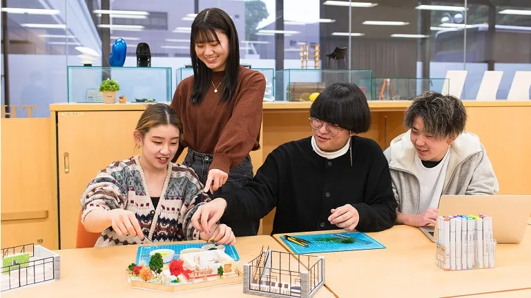 住宅模型を使いながら話し合う学生たち