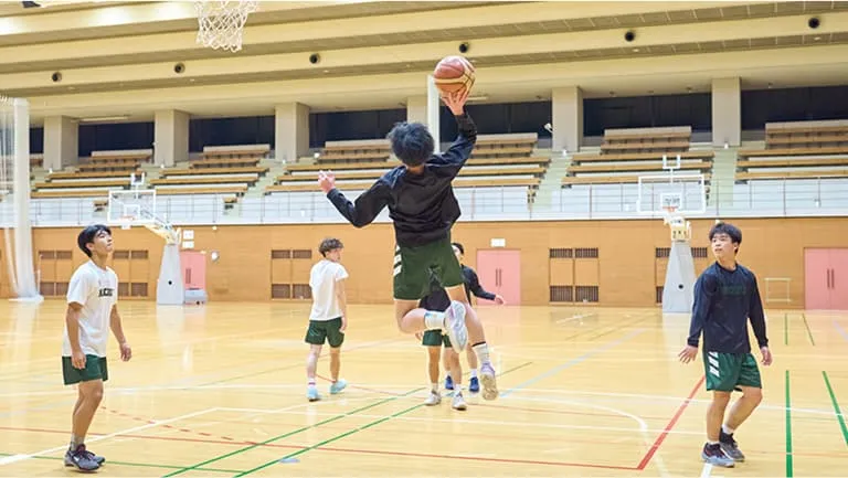 ゴール横の角度から高くジャンプしてシュートを決める練習をする生徒