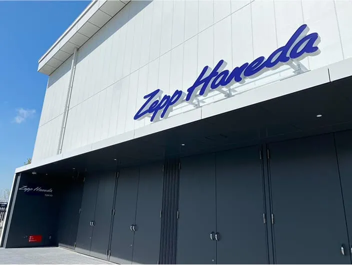 白い外壁に青い筆記体のロゴが掲げられた建物