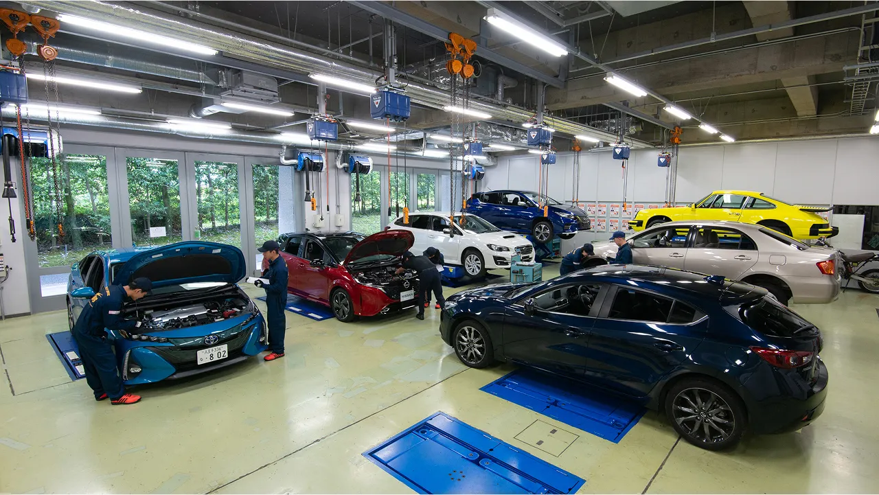 ずらりと並んだ自動車と学生たちが実習を受けている様子