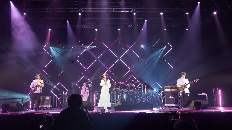 学生が照明に照らされたステージでライブパフォーマンスをする様子