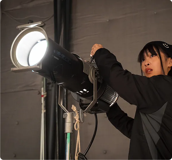スタジオ照明のスポットライトを調整する学生